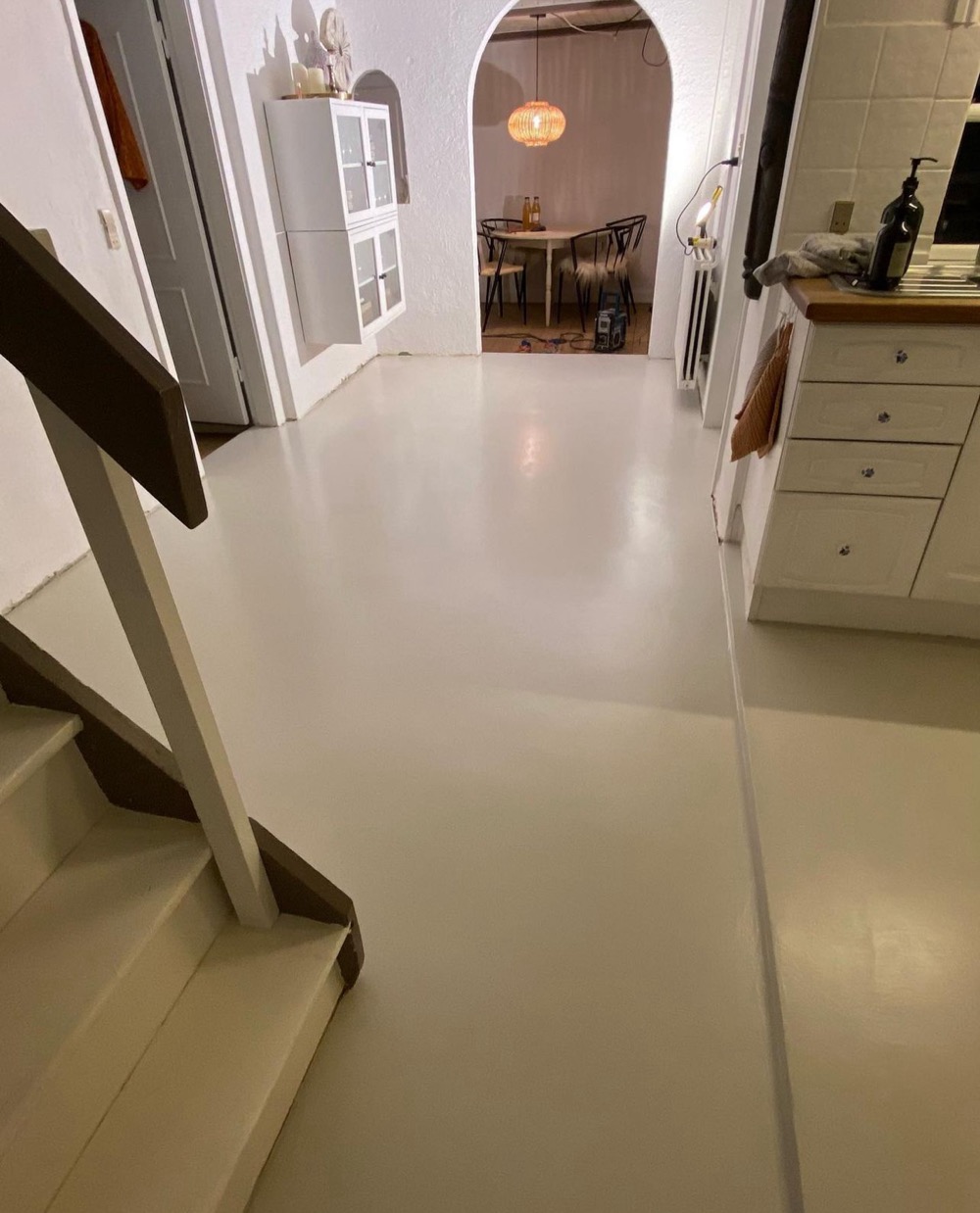 After: the same kitchen and stair landing finished in seamless cream microcement with no grout lines